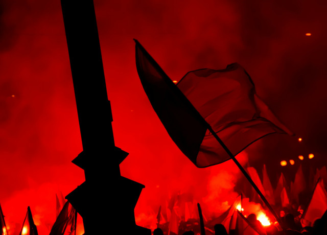 Drapeau flottant devant un monument avec des torches rouges allumées